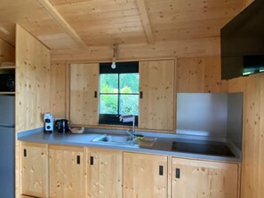A wooden kitchen with a window, cabinets, and a sink.