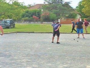 A group of people playing a game on a paved outdoor area with a car and greenery in the background. - Cozy mobile home - 4 guests (Verteillac)