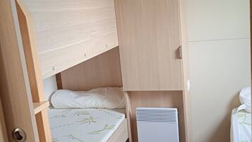 A bunk bed with a mattress featuring a leaf pattern, a white pillow, and a white heater unit.