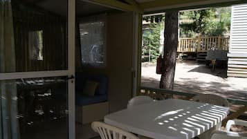 Un patio techado con una mesa, sillas, un sofá azul y vistas al exterior.