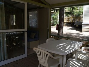 Un patio techado con una mesa, sillas, un sofá azul y vistas al exterior.