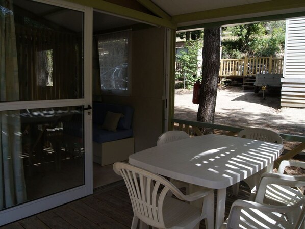 A covered patio area with a table and chairs, a blue sofa, and a view of the outside.