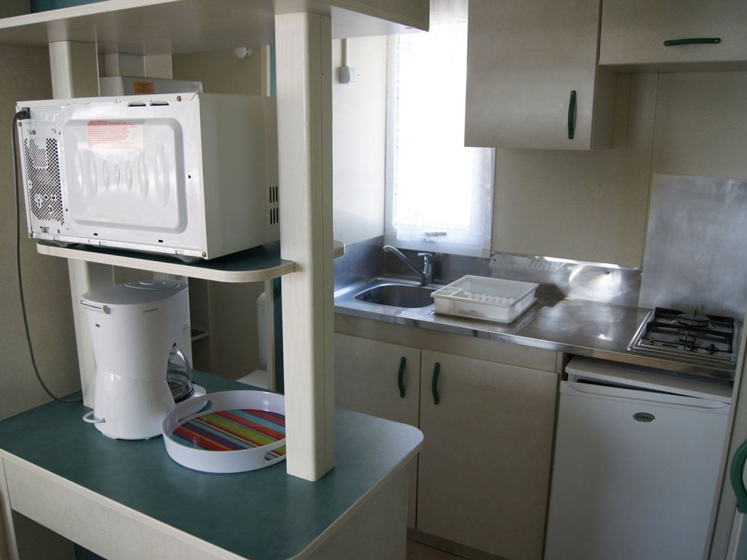 Una kitchenette equipada con microondas, cafetera y un refrigerador pequeño.