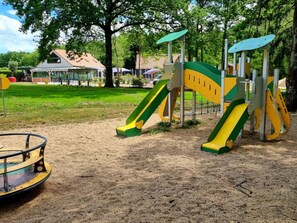Ein Spielplatz mit Rutschen und Schaukeln in einem Park.