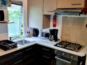 Eine kleine Küche mit Gasherd, Kaffeemaschine und Spüle.