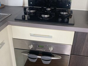 Ett kök med en spis, en ugn och en digital klocka som visar 15:54.