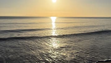 A sunset over a calm sea with gentle waves.