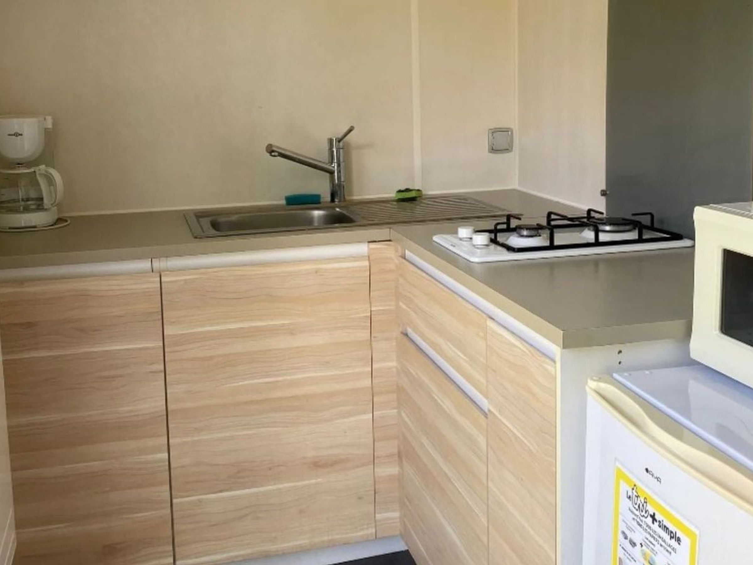 Une cuisine de taille réduite, équipée d’un évier, d’une cuisini ère et d’un four à micro-ondes.