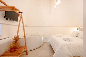 Habitació d'hotel amb un llit, una banca de fusta, una televisió i una banyera.