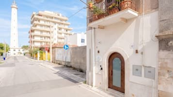 Una calle con un edificio blanco, una señal de stop y un faro a lo lejos.