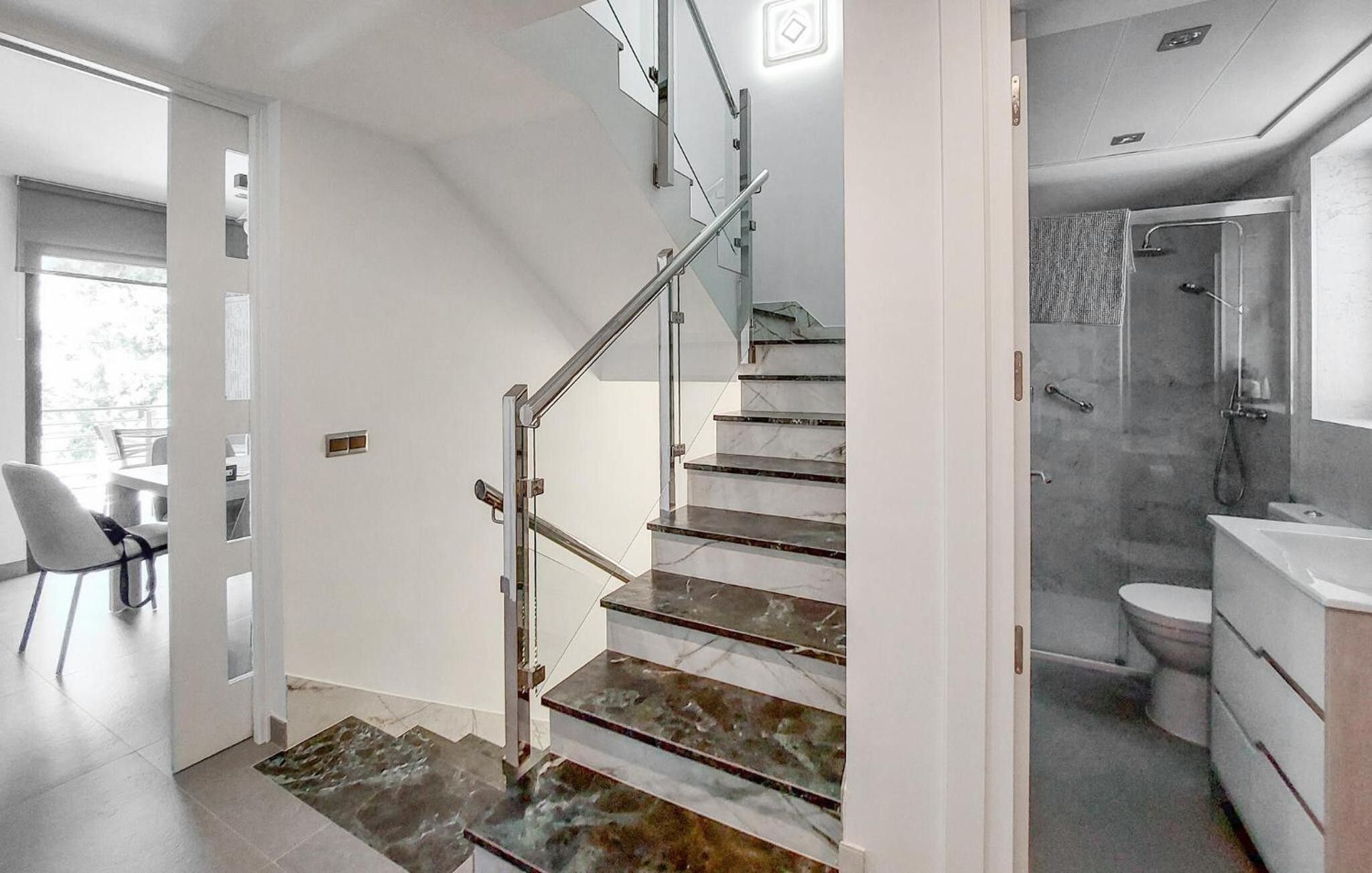 A modern interior with a staircase, a bathroom, and a dining area.