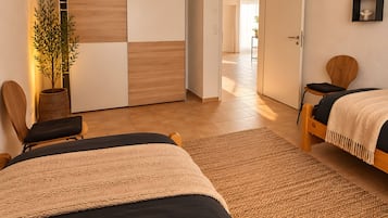 A modern bedroom with two beds, a large window, and a view of a hallway.