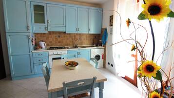 Una cucina con mobili azzurri, un tavolo da pranzo con sedie e un vaso con girasoli.