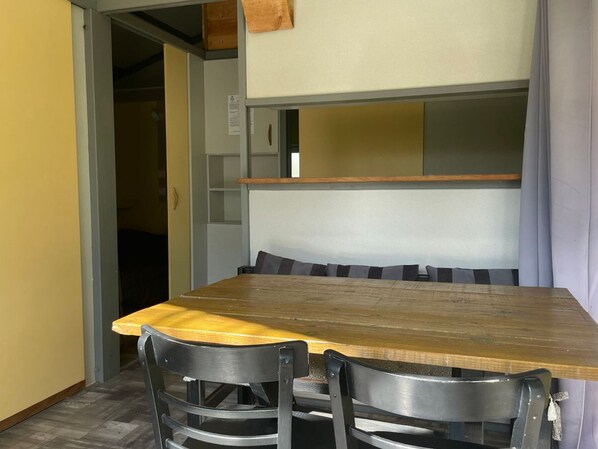 A dining area with a wooden table, two chairs, a bench, and a wall-mounted shelf.