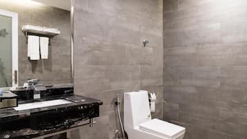 A bathroom with a black marble sink, a white toilet, and grey tiled walls.