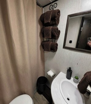 Un baño con inodoro, lavamanos y toallero con toallas.