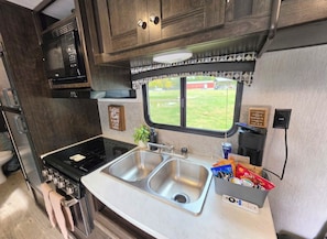 Una cocina con un lavaplatos doble, un microondas y una ventana con vistas al exterior.