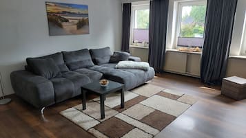 Un salon moderne avec un canapé gris, une petite table et un tapis à motifs.