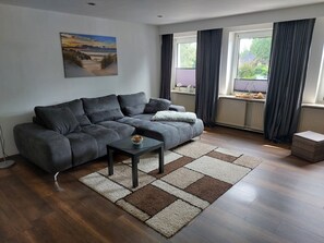 A modern living room with a grey sofa, a small table, and a patterned rug. - Quiet self-contained apartment with terrace and parking (Heide)