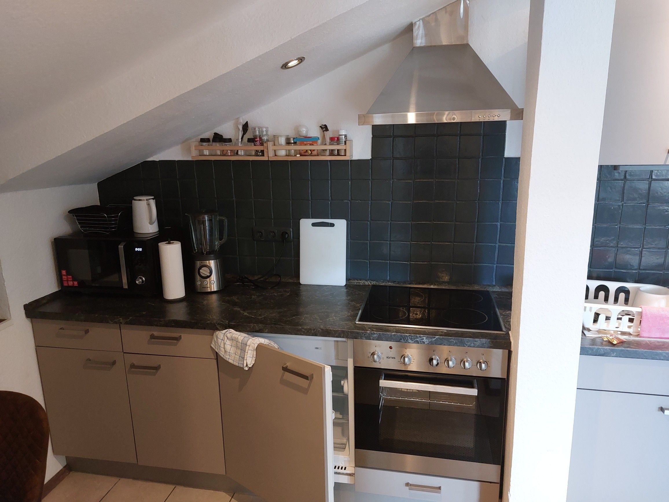 Eine kompakte Küche mit eingebautem Backofen, Kochfeld und Mikrowelle.