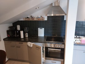 Eine kompakte Küche mit eingebautem Backofen, Kochfeld und Mikrowelle.