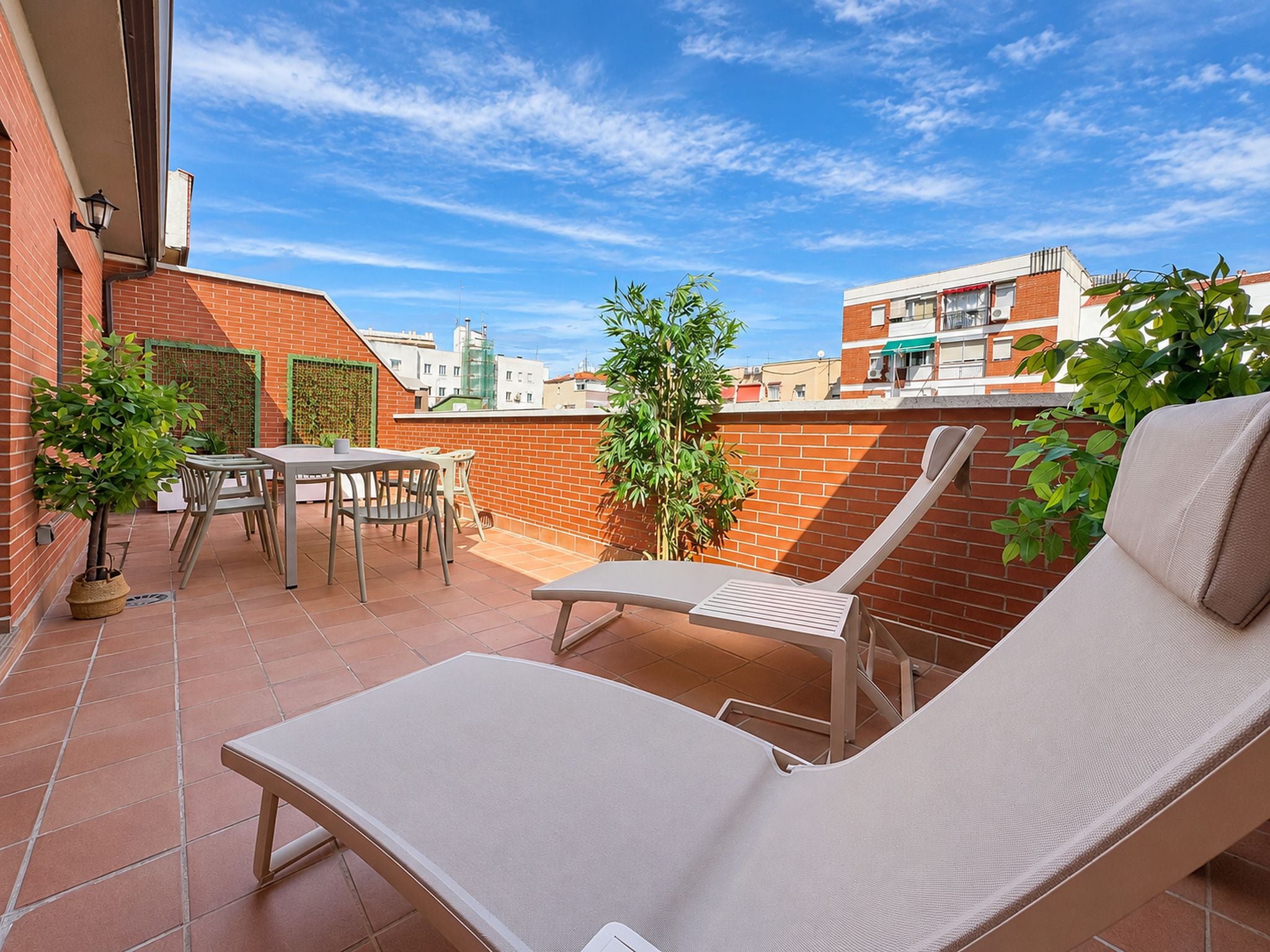 Un patio al aire libre con una mesa y sillas, una silla de descanso y una planta en maceta.