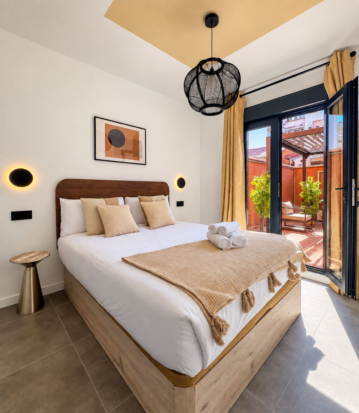 Un dormitorio moderno con una cama grande, una mesita de noche, una lámpara de pared y vistas al exterior.