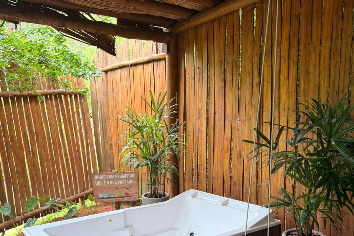 A wooden deck with a hot tub, potted plants, and a wooden fence.