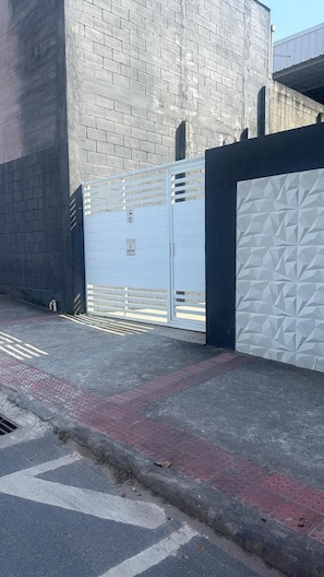 A gated entrance with a metal gate and a white wall with geometric patterns. - New Listing (Vila Velha)
