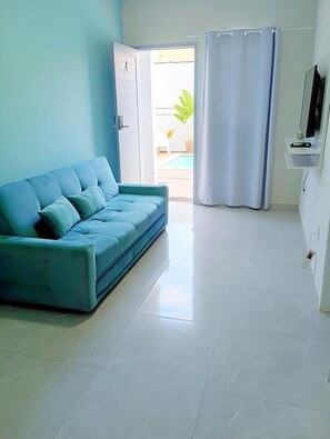 A room with a sofa, a door leading to a balcony, and a curtain. - New Listing (Vila Velha)