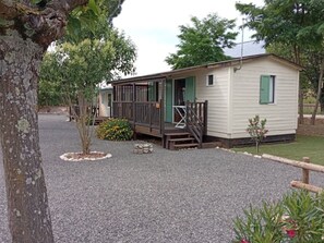 Une petite maison mobile de plain-pied, dotée d’une véranda et d’un petit jardin.