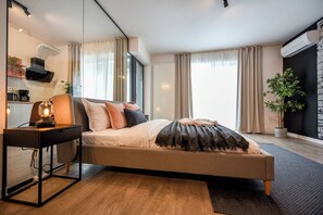 Ein modernes Schlafzimmer mit Bett, Nachttisch, Lampe und Blick ins Freie.