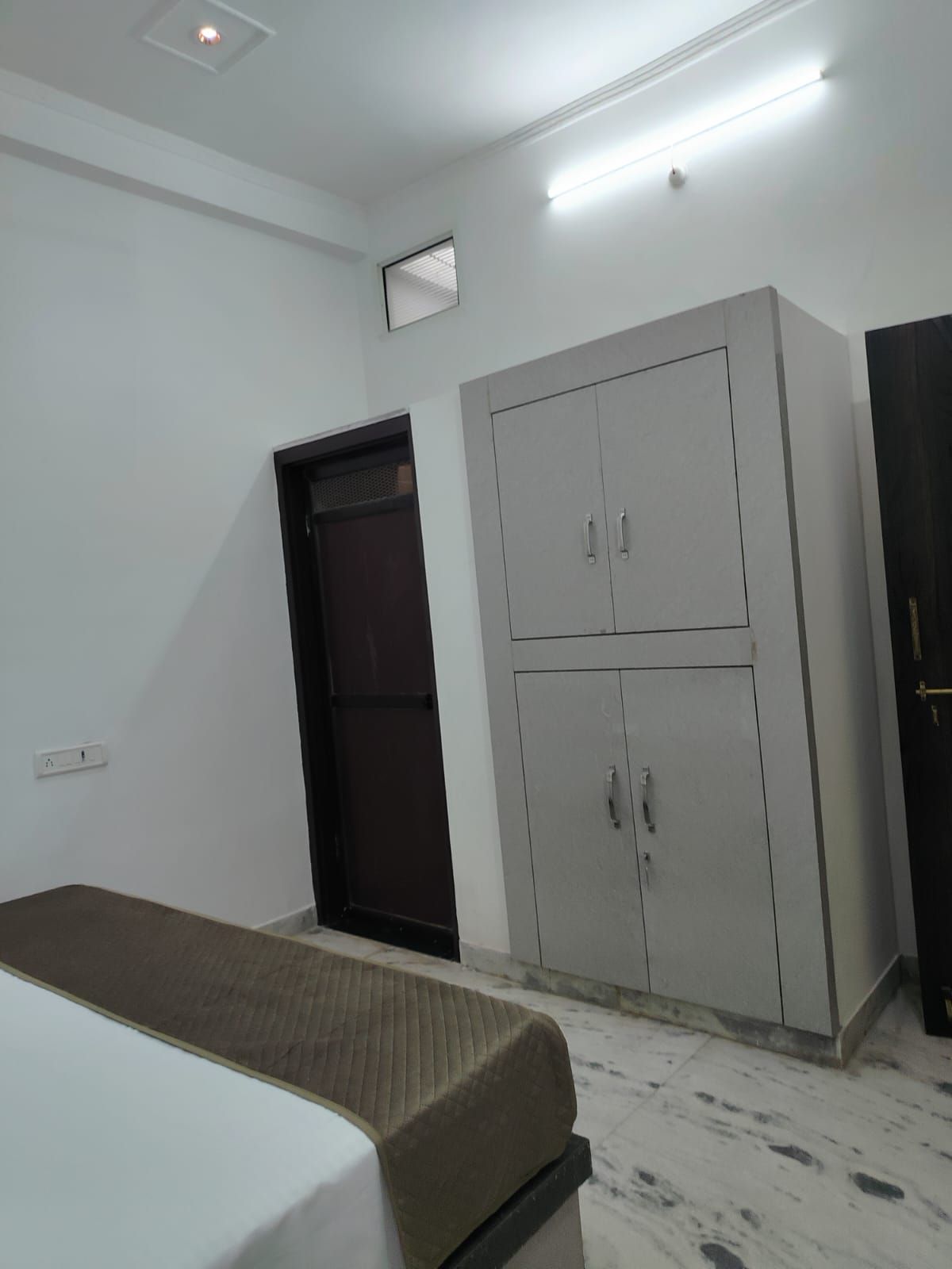 Quarto com cama, guarda-roupa e porta.