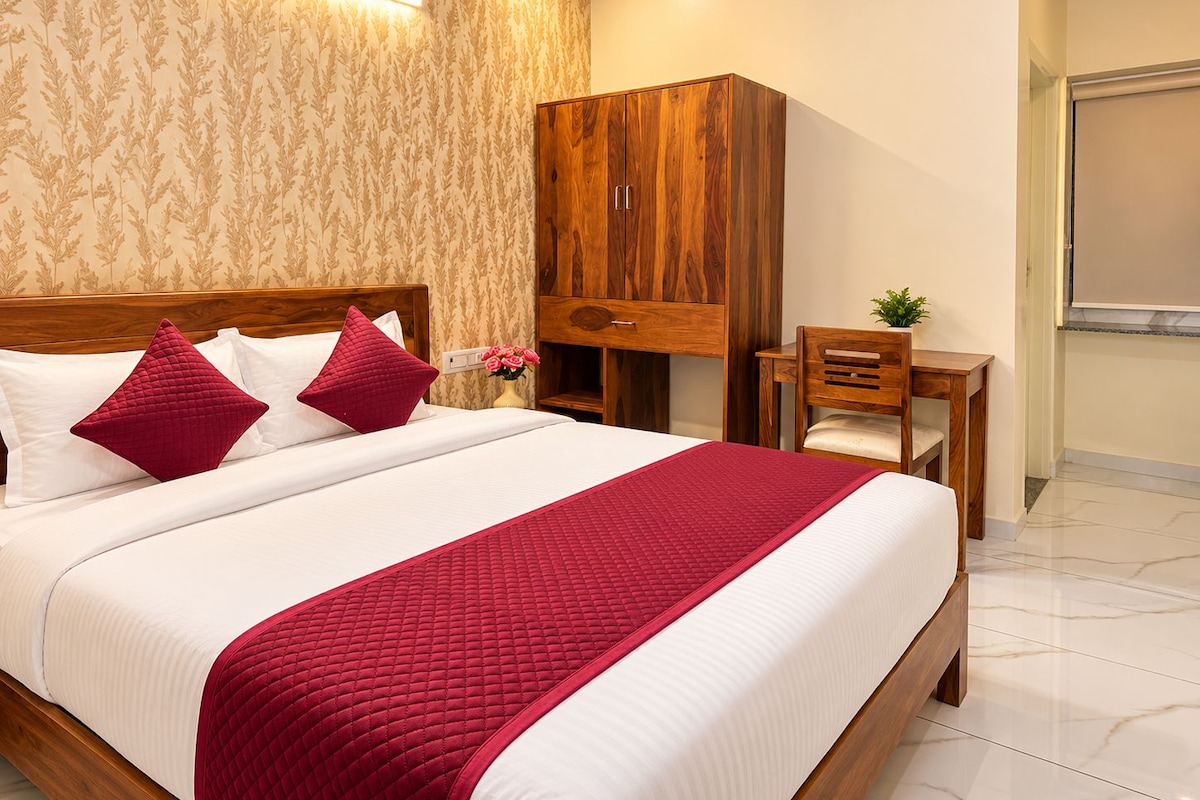 Una habitación de hotel con una cama grande, cabecero de madera, un escritorio y un armario.