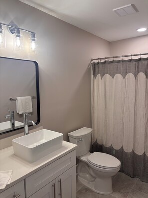 Un baño con lavamanos blanco, inodoro y cortina de ducha.