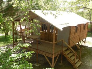Une cabane en bois avec un balcon, un escalier et une petite table.