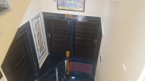 A reception area with a reception desk, a framed picture on the wall, and a red carpet leading to a door. - Hotel vishnu villas (Gaya)