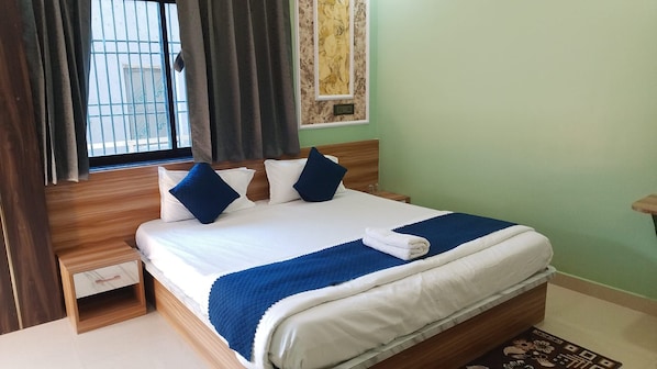 A neatly made bed with a blue and white bedspread, a wooden headboard, and a nightstand with a drawer.