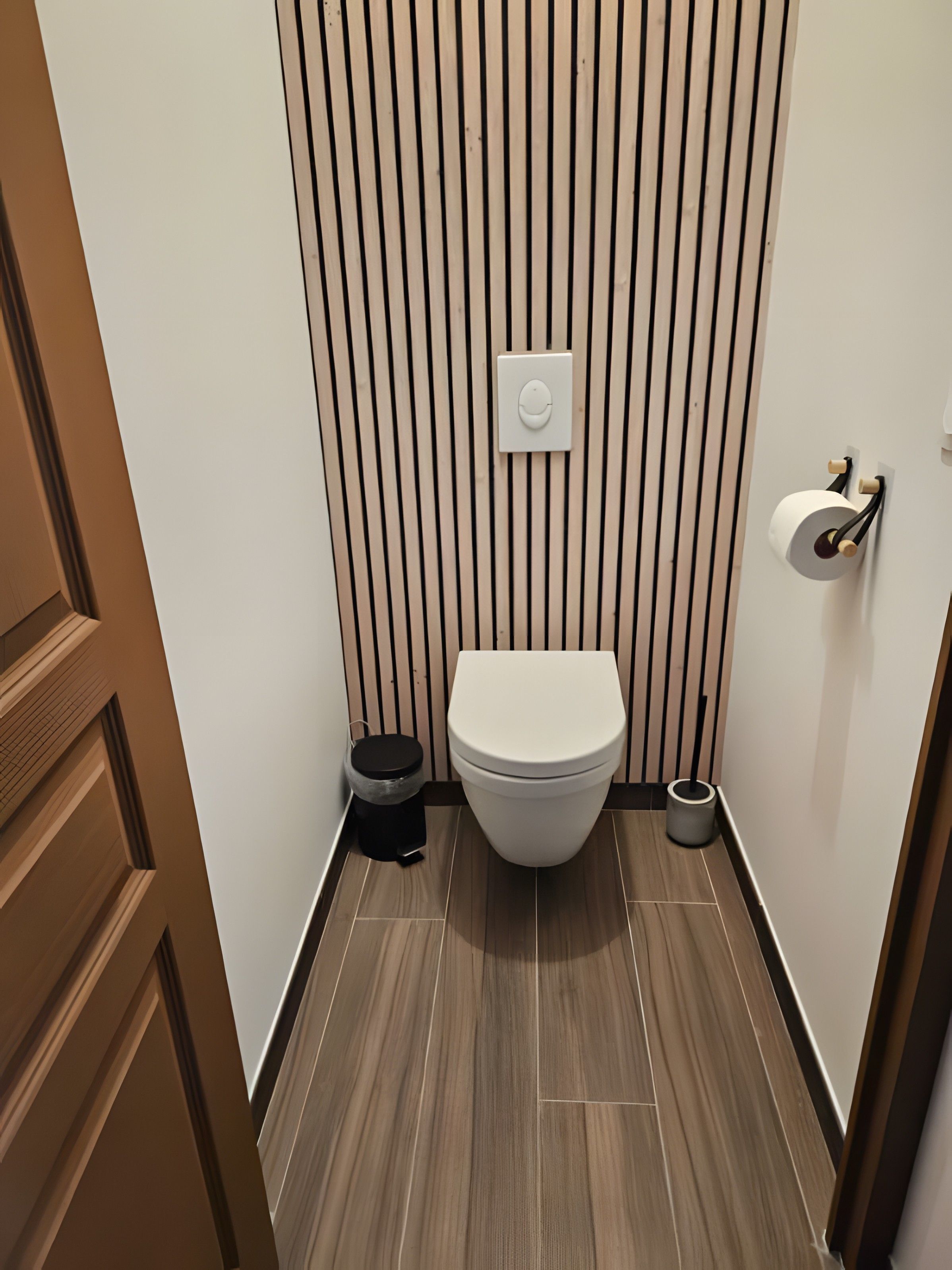 Een moderne badkamer met een toilet, een prullenbak en een toiletrolhouder.