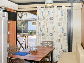 Ein Zimmer mit einem Holztisch, Stühlen, einer Glasvase und einem Vorhang mit Fischmuster.