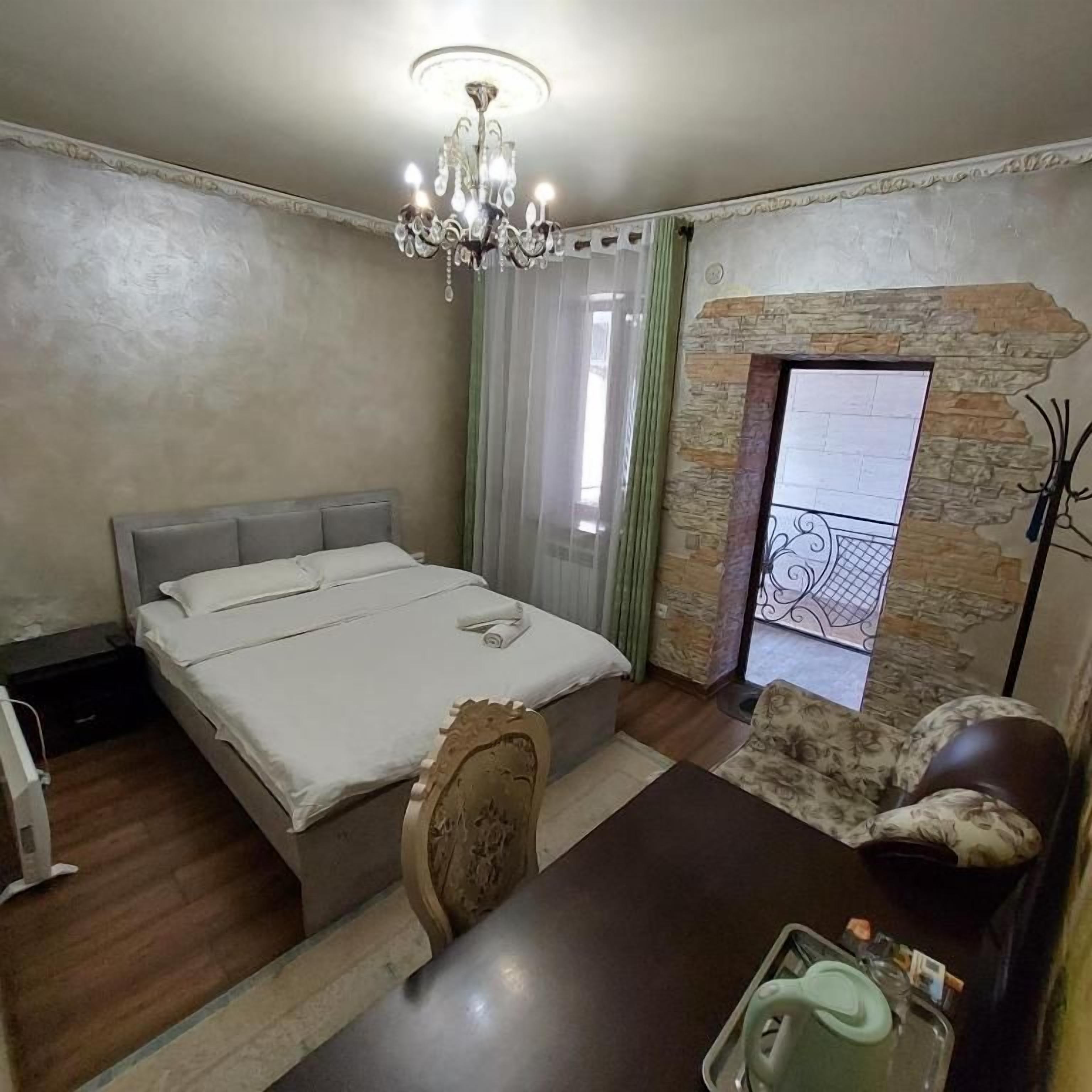 A bedroom with a bed, a chandelier, a fireplace, a dining table, and a chair.