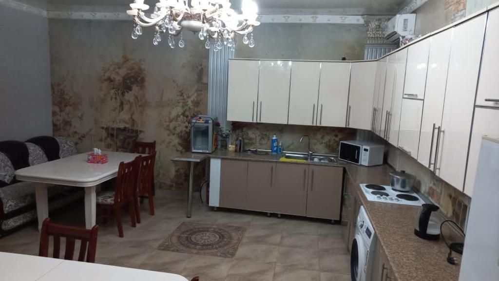 A compact kitchen with a dining area, a chandelier, and basic appliances.