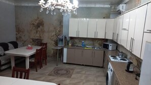 A compact kitchen with a dining area, a chandelier, and basic appliances. - Camelot (Bishkek)
