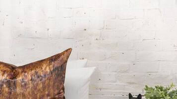 A white brick wall with a large yellow abstract painting, a framed picture of a person with a dog, and a black French Bulldog on a checkered table.