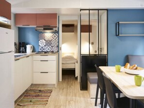 A compact kitchen with white cabinets, a coffee maker, and a patterned backsplash. - Mobile home with terrace - 6 guests (Séez)