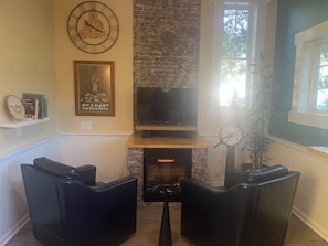 Un salon avec une cheminée, une horloge et un téléviseur.