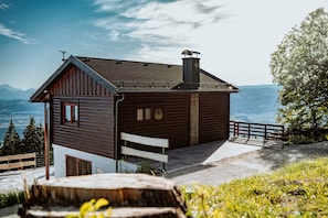 A wooden cabin with a sloped roof, a chimney, and a view of mountains.