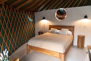 Ett sovrum med en säng i trä, en rund väggdekoration och två sänglampor.