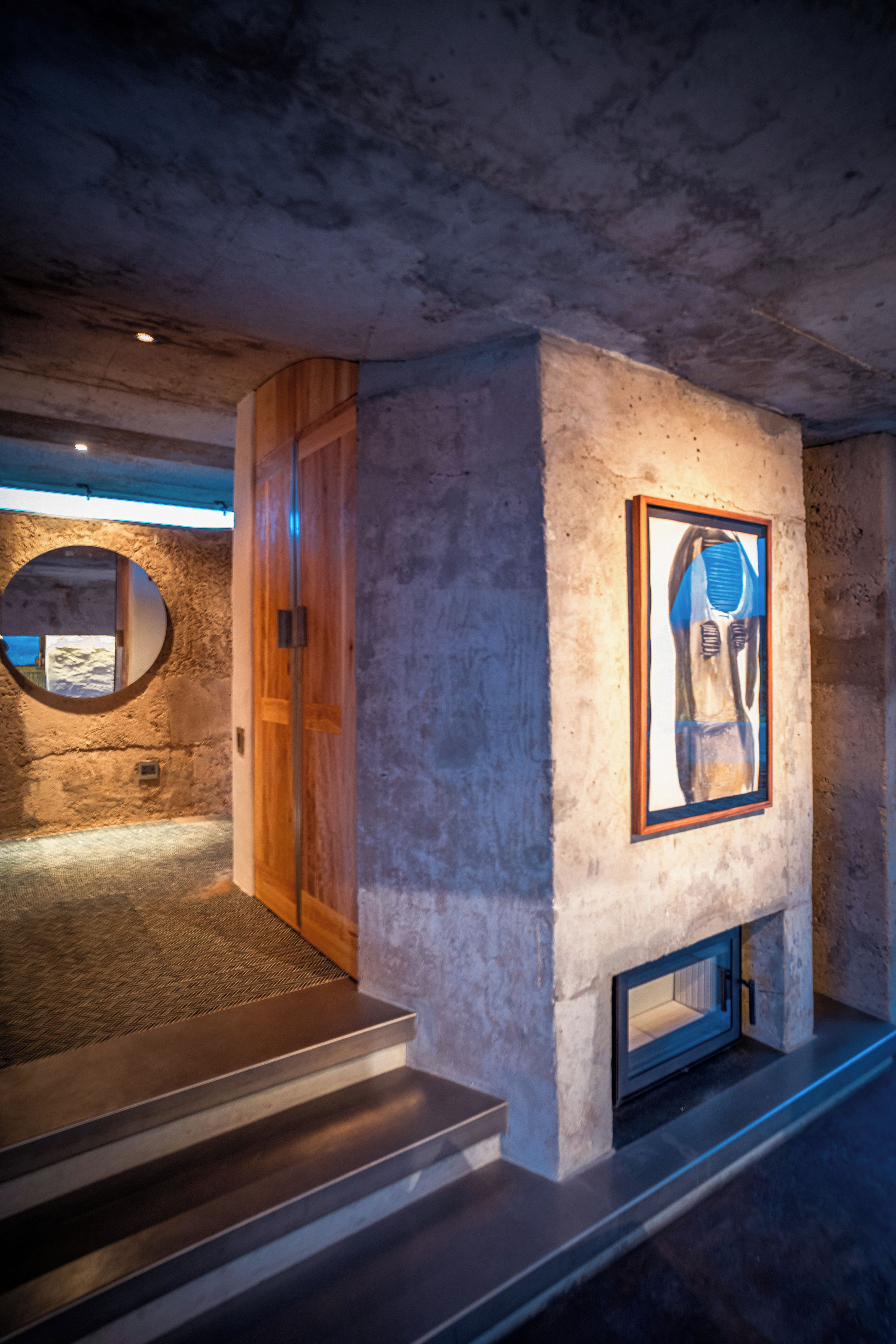 A modern interior with a fireplace, a framed artwork, and a wooden door.