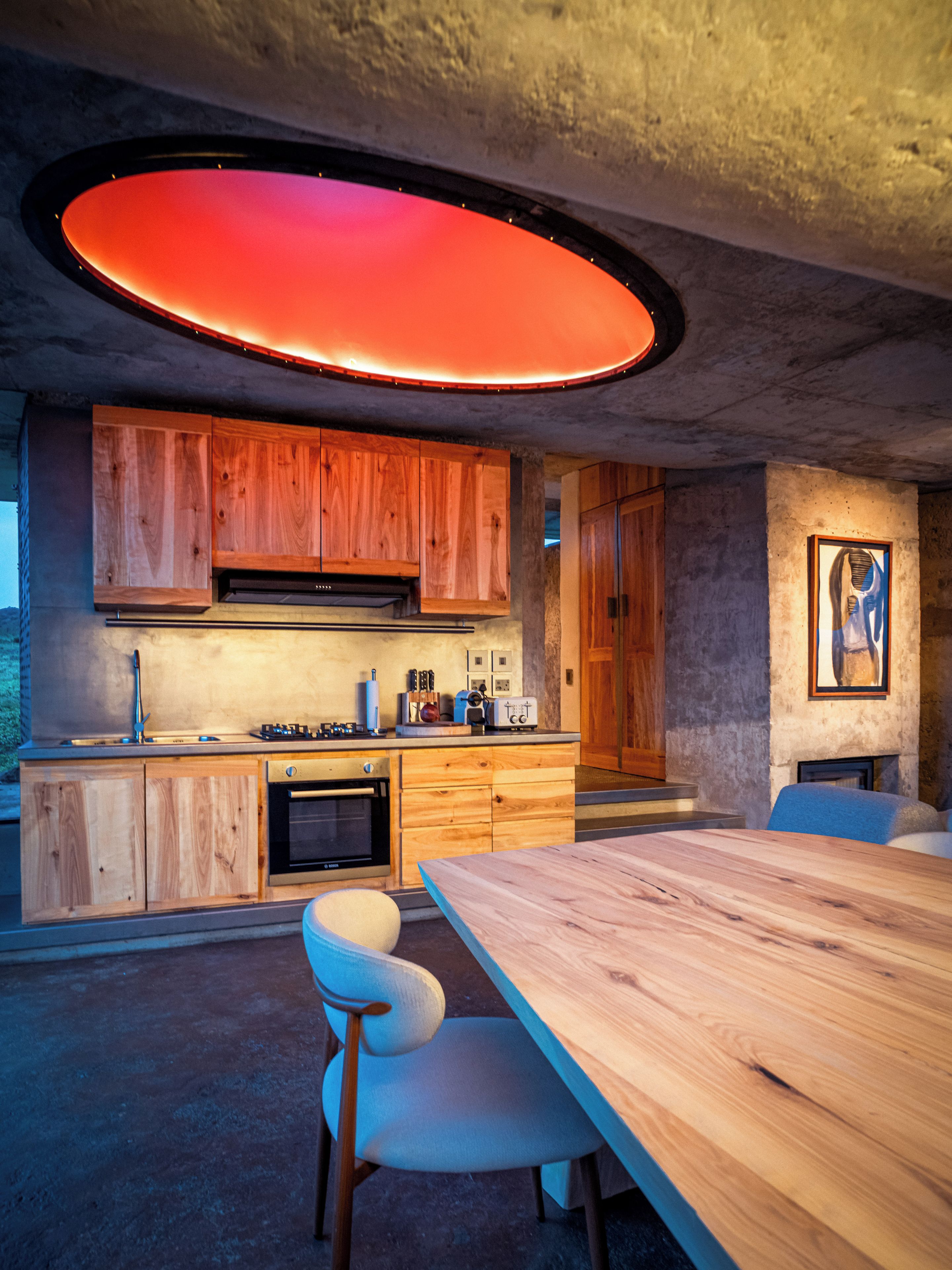 A modern kitchen with wooden cabinets, a dining table, and a large circular light fixture.